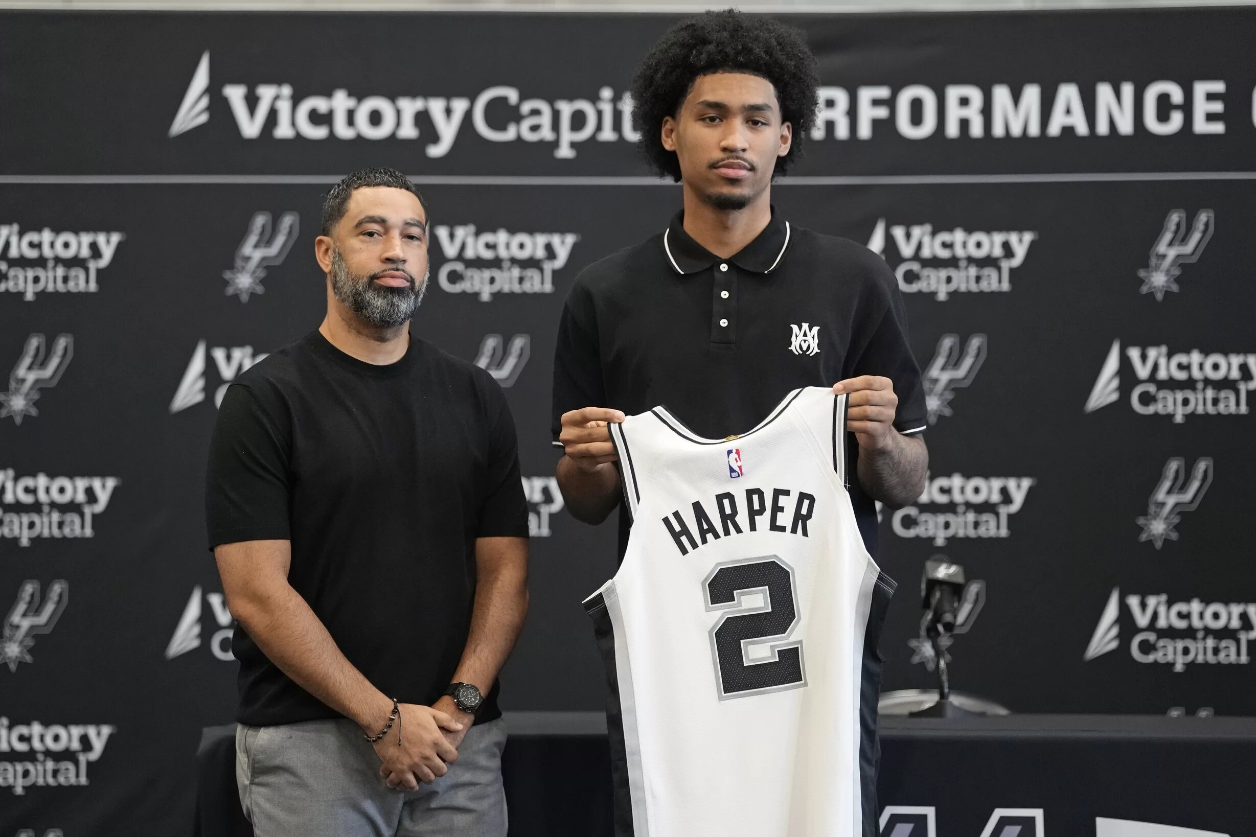 San Antonio first round draft pick Dylan Harper (2) holds up his jersey along with general manager Brian Wright at Victory Capital Performance Center.