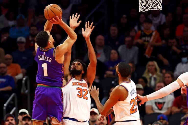 Nov 20, 2024; Phoenix, Arizona, USA; Phoenix Suns guard Devin Booker (1) shoots the ball against New York Knicks center Karl-Anthony Towns (32) during the third quarter at Footprint Center. Mandatory Credit: Mark J. Rebilas-Imagn Images