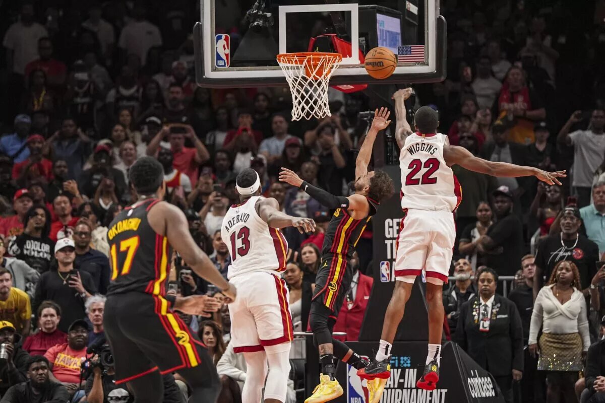 Apr 18, 2025; Atlanta, Georgia, USA; Atlanta Hawks guard Trae Young (11) ties the game in the final seconds behind Miami Heat forward Andrew Wiggins (22) during the second half at State Farm Arena. Mandatory Credit: Dale Zanine-Imagn Images