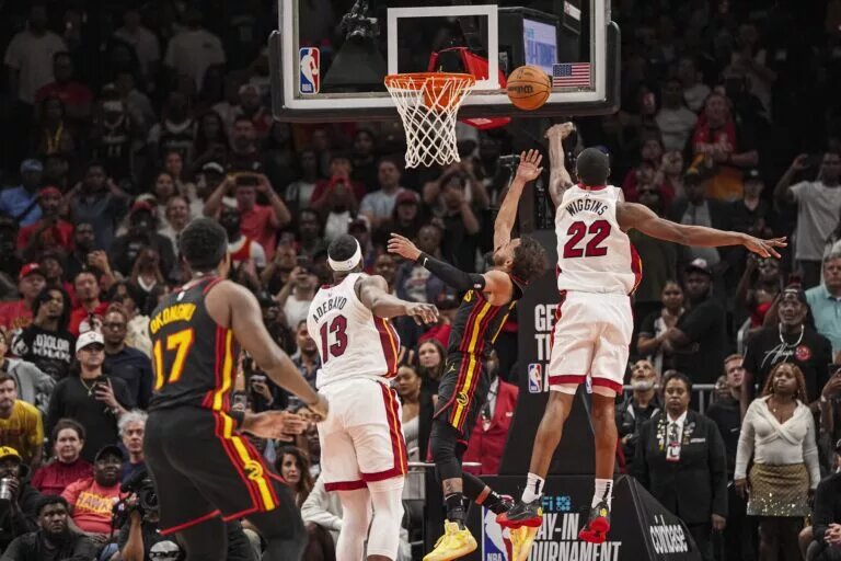 Apr 18, 2025; Atlanta, Georgia, USA; Atlanta Hawks guard Trae Young (11) ties the game in the final seconds behind Miami Heat forward Andrew Wiggins (22) during the second half at State Farm Arena. Mandatory Credit: Dale Zanine-Imagn Images