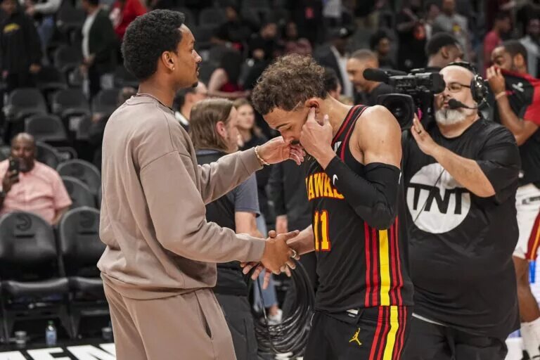 Atlanta Hawks guard Trae Young (11) reacts with injured player Kobe Bufkin