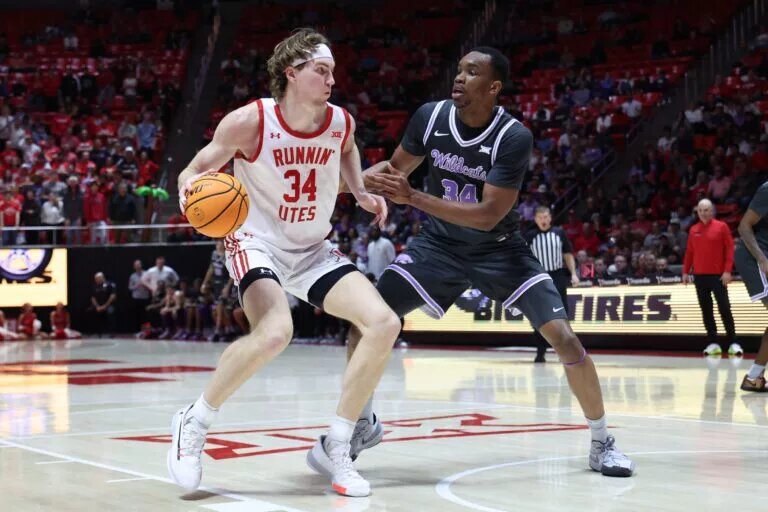 Feb 17, 2025; Salt Lake City, Utah, USA; Utah Utes center Lawson Lovering (left) dribbles against Kansas State Wildcats center Ugonna Onyenso (right) during the second half at Jon M. Huntsman Center. Mandatory Credit: Rob Gray-Imagn Images