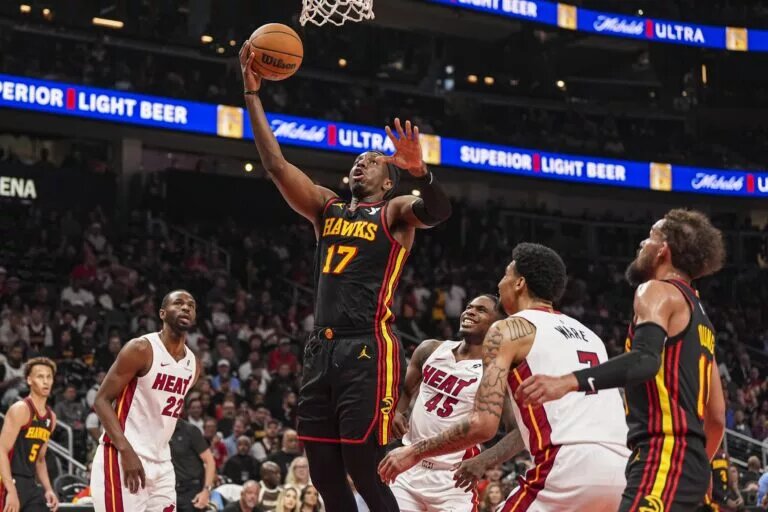 Apr 18, 2025; Atlanta, Georgia, USA; Atlanta Hawks forward Onyeka Okongwu (17) goes to the basket behind Miami Heat guard Davion Mitchell (45) during the first half at State Farm Arena. Mandatory Credit: Dale Zanine-Imagn Images