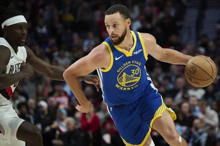Oct 14, 2025; Portland, Oregon, USA; Golden State Warriors guard Stephen Curry (30) drives past Portland Trail Blazers guard Jrue Holiday (5) during the first half at Moda Center. Mandatory Credit: Troy Wayrynen-Imagn Images
