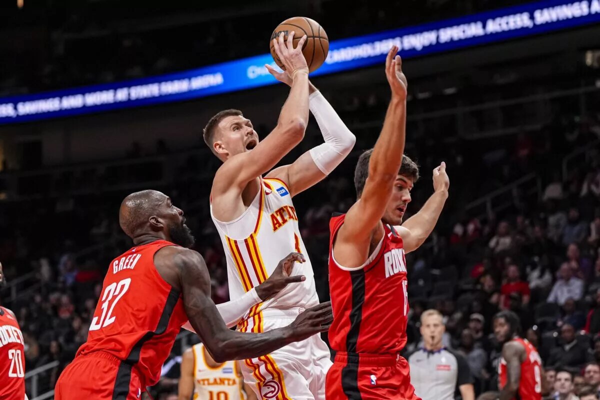Oct 16, 2025; Atlanta, Georgia, USA; Atlanta Hawks center Kristaps Porzingis (8) goes to the basket between Houston Rockets forward Jeff Green (32) and guard Reed Sheppard (15) during the first half at State Farm Arena. Mandatory Credit: Dale Zanine-Imagn Images
