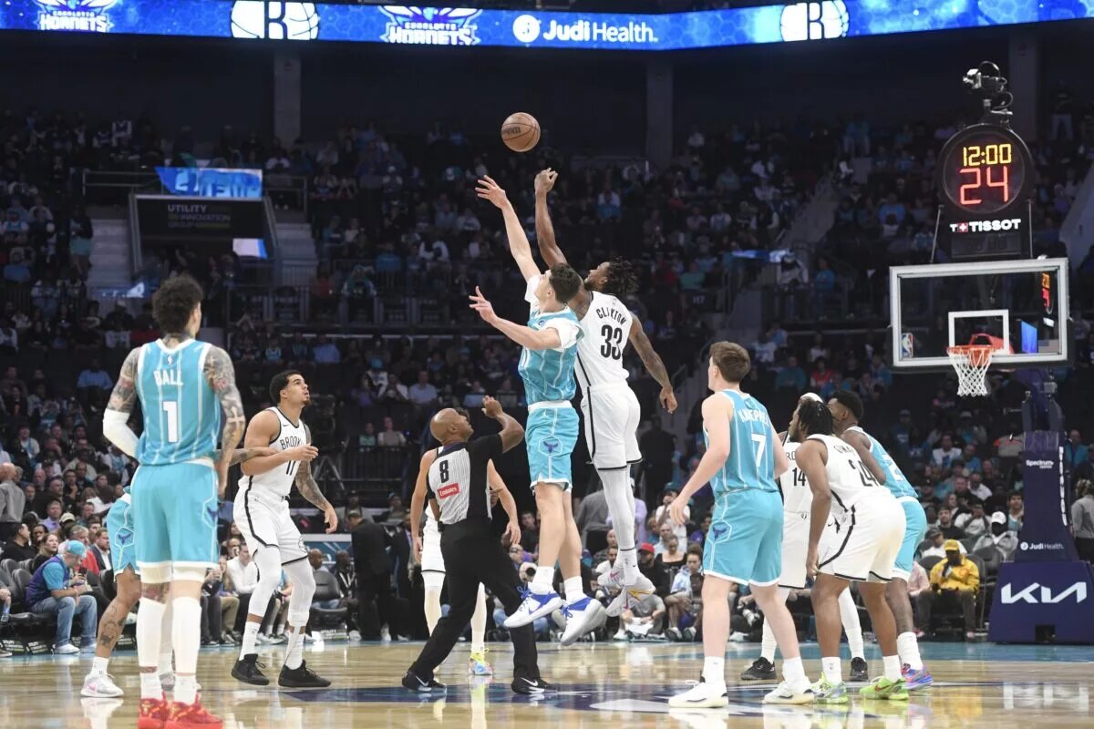 Oct 22, 2025; Charlotte, North Carolina, USA; Charlotte Hornets center Ryan Kalkbrenner (11) and Brooklyn Nets center Nic Claxton (33) tip off the game at the Spectrum Center. Mandatory Credit: Sam Sharpe-Imagn Images