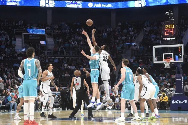 Oct 22, 2025; Charlotte, North Carolina, USA; Charlotte Hornets center Ryan Kalkbrenner (11) and Brooklyn Nets center Nic Claxton (33) tip off the game at the Spectrum Center. Mandatory Credit: Sam Sharpe-Imagn Images