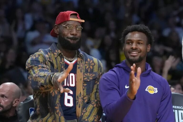 Oct 24, 2025; Los Angeles, California, USA; Los Angeles Lakers forward LeBron James (left) and son Bronny James watch from the bench in the second half against the Minnesota Timberwolves at Crypto.com Arena. Mandatory Credit: Kirby Lee-Imagn Images