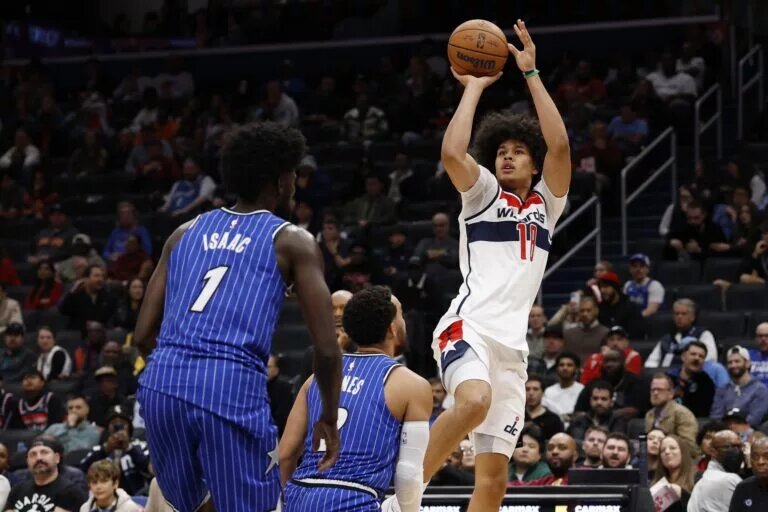 Nov 1, 2025; Washington, District of Columbia, USA; Washington Wizards forward Kyshawn George (18) shoots the ball over Orlando Magic guard Tyus Jones (2) in the second half at Capital One Arena. Mandatory Credit: Geoff Burke-Imagn Images