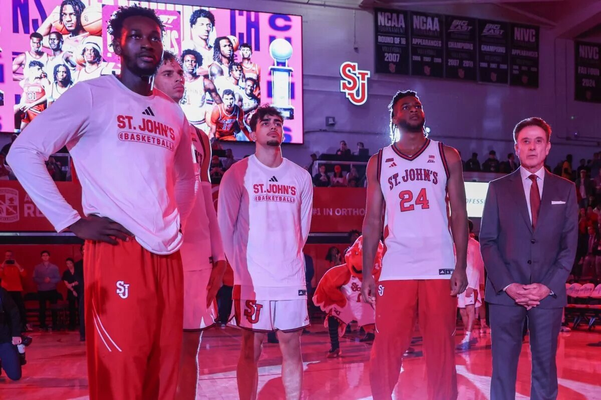 Nov 3, 2025; Queens, New York, USA; St. John's Red Storm forwards Sadiku Ibine Ayo (2), Rubén Prey (17), guard Lefteris Liotopoulos (31) and forward Zuby Ejiofor (24) stand with head coach Rick Pitino prior to the raising of the 2025 Big East Championship banner at Carnesecca Arena. Mandatory Credit: Wendell Cruz-Imagn Images