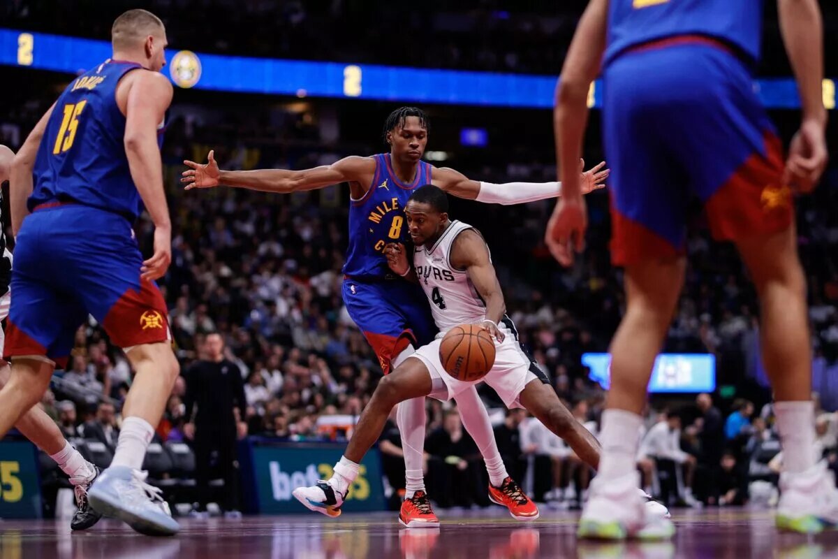 San Antonio Spurs guard De'Aaron Fox (4) controls the ball under pressure from Denver Nuggets guard Peyton Watson (8) as center Nikola Jokic (15) defends in the third quarter at Ball Arena.