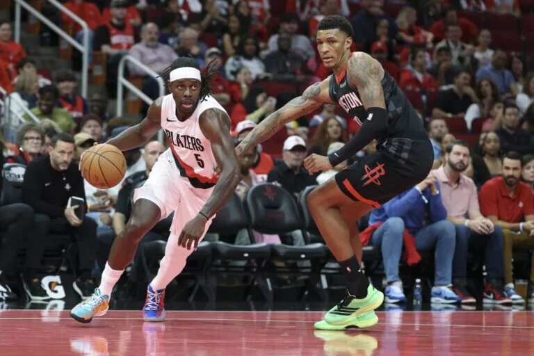 Nov 14, 2025; Houston, Texas, USA; Portland Trail Blazers guard Jrue Holiday (5) dribbles the ball as Houston Rockets forward Jabari Smith Jr. (10) defneds during the third quarter at Toyota Center. Mandatory Credit: Troy Taormina-Imagn Images