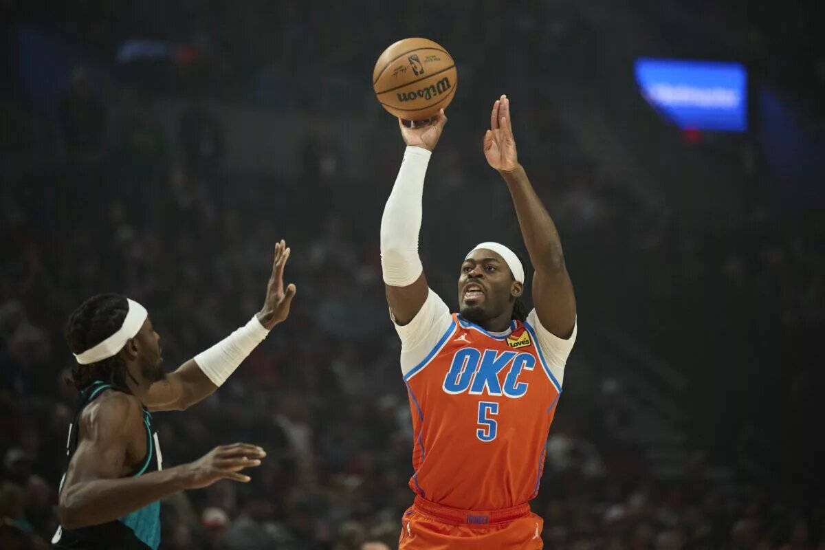 Nov 30, 2025; Portland, Oregon, USA; Oklahoma City Thunder guard Luguentz Dort (5) shoots a jump shot during the first half against Portland Trail Blazers forward Jerami Grant (9) at Moda Center. Mandatory Credit: Troy Wayrynen-Imagn Images