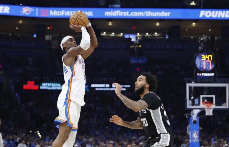 Dec 25, 2025; Oklahoma City, Oklahoma, USA; Oklahoma City Thunder guard Shai Gilgeous-Alexander (2) shoots a three point basket over San Antonio Spurs forward Julian Champagnie (30) during the second half at Paycom Center. Mandatory Credit: Alonzo Adams-Imagn Images
