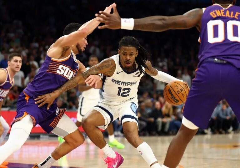 Memphis Grizzlies guard Ja Morant dribbles against Phoenix Suns defenders Devin Booker and Royce O'Neale