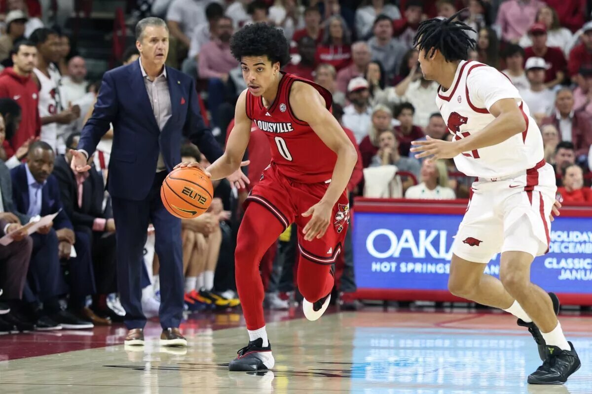 Louisville Cardinals guard Mikel Brown Jr (0) drives against Arkansas Razorbacks guard D.J. Wagner (21) as head coach John Calipari watches during the second half at Bud Walton Arena. Arkansas won 89-80.