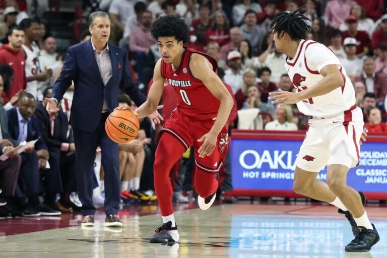 Louisville Cardinals guard Mikel Brown Jr (0) drives against Arkansas Razorbacks guard D.J. Wagner (21) as head coach John Calipari watches during the second half at Bud Walton Arena. Arkansas won 89-80.