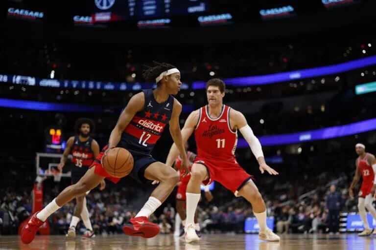 Jan 19, 2026; Washington, District of Columbia, USA; Washington Wizards guard Tre Johnson (12) drives to the basket as LA Clippers center Brook Lopez (11) defends in the first half at Capital One Arena. Mandatory Credit: Geoff Burke-Imagn Images