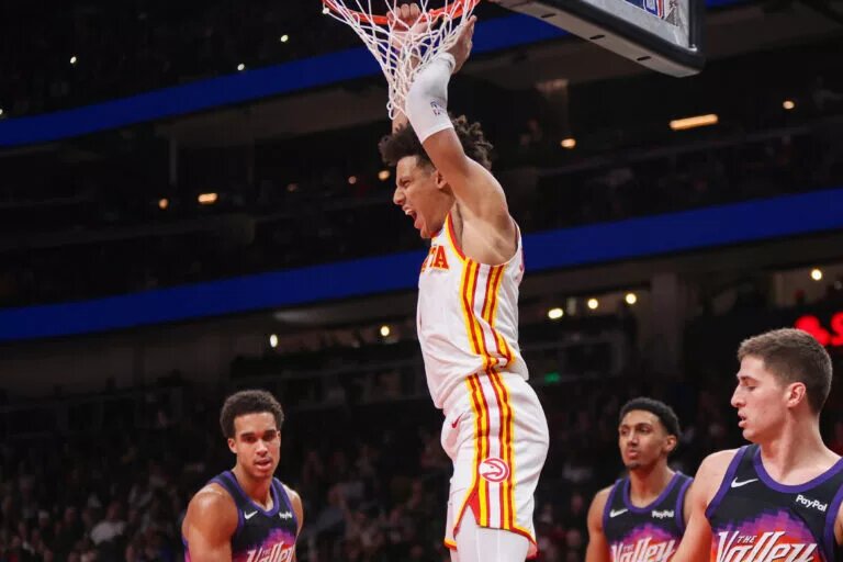Atlanta Hawks forward Jalen Johnson hangs on rim and emotes after dunk