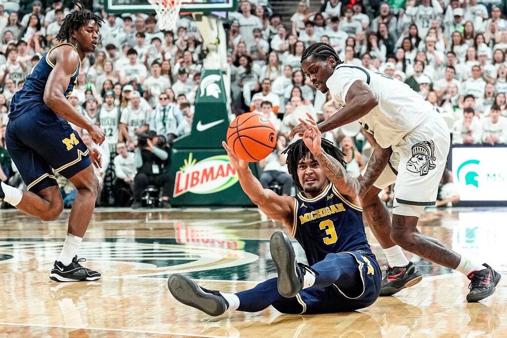 Michigan guard Elliot Cadeau (3) and Michigan State forward Coen Carr (55) battle for the ball during the first half at Breslin Center in East Lansing on Friday, Jan. 30, 2026.