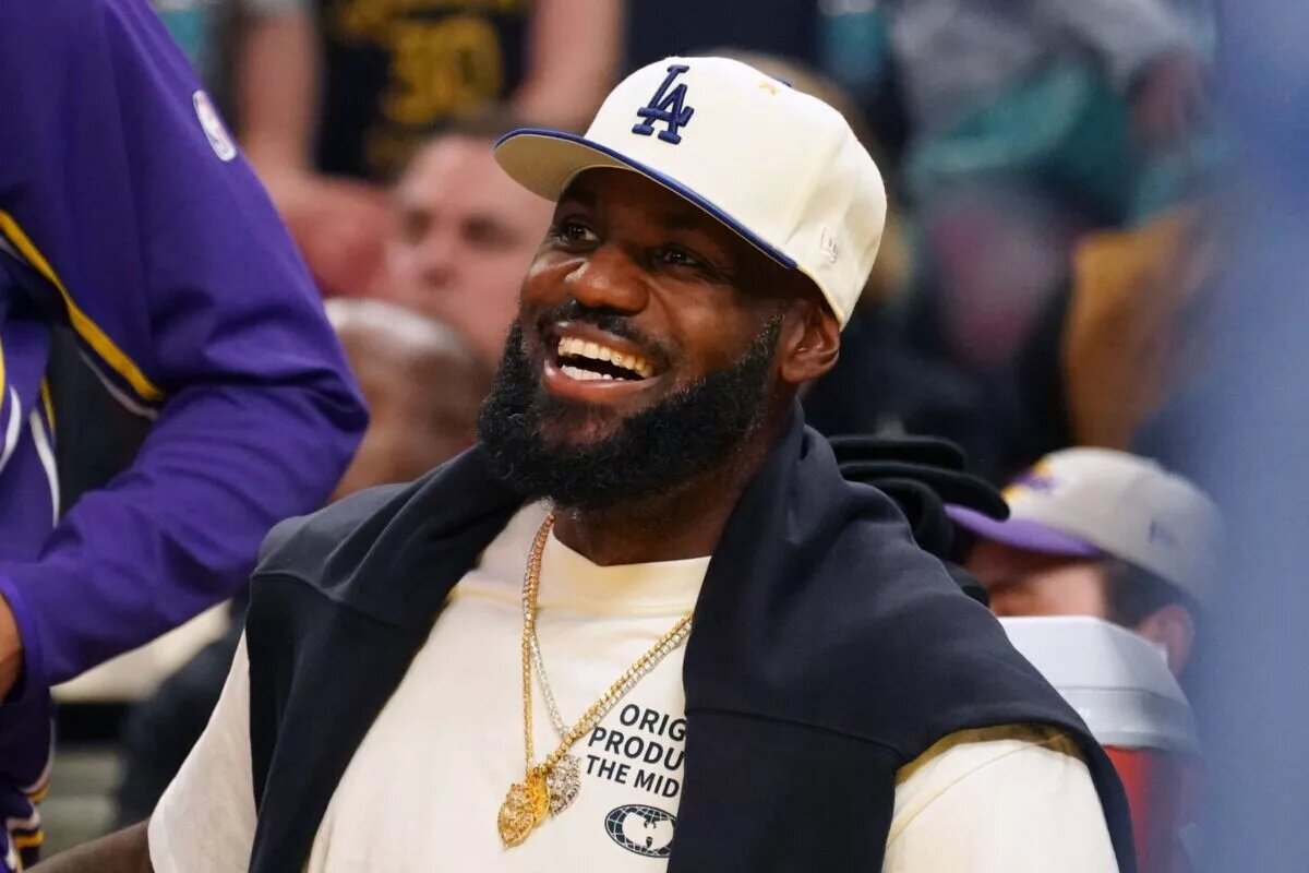 Oct 5, 2025; San Francisco, California, USA; Los Angeles Lakers forward LeBron James (23), wearing a Los Angeles Dodgers hat, smiles after watching his son, guard Bronny James (9), dunk a rebound against the Golden State Warriors in the third quarter at Chase Center. Mandatory Credit: David Gonzales-Imagn Images