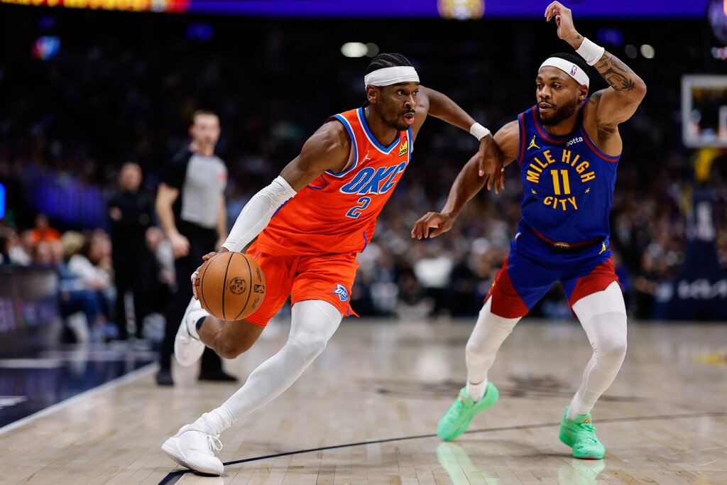 Oklahoma City Thunder guard Shai Gilgeous-Alexander (2) controls the ball as Denver Nuggets guard Bruce Brown (11) guards in the second quarter at Ball Arena.