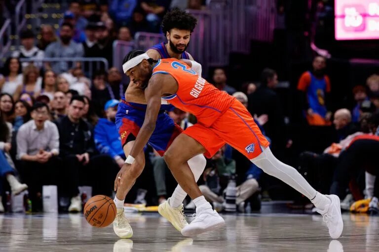 Oklahoma City Thunder guard Shai Gilgeous-Alexander (2) controls the ball under pressure from Denver Nuggets guard Jamal Murray (27) in the fourth quarter at Ball Arena.