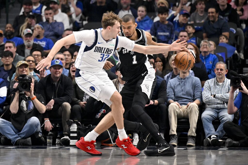 Feb 5, 2026; Dallas, Texas, USA; San Antonio Spurs forward Victor Wembanyama (1) moves the basket past Dallas Mavericks forward Cooper Flagg (32) during the first quarter at the American Airlines Center. Mandatory Credit: Jerome Miron-Imagn Images