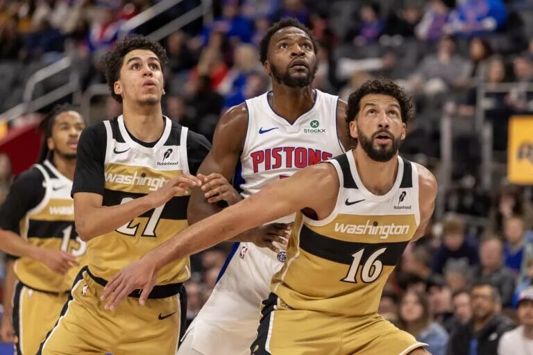 Detroit Pistons forward Paul Reed (7) battles for position between Washington Wizards guard Will Riley (27) and forward Anthony Gill (16) during the second half at Little Caesars Arena.