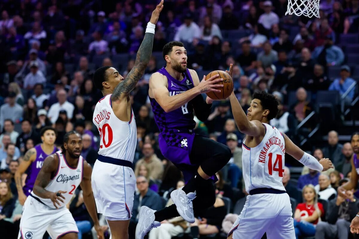 Sacramento Kings guard Zach LaVine goes up for acrobatic layup while three Los Angeles Clippers players try to stop him
