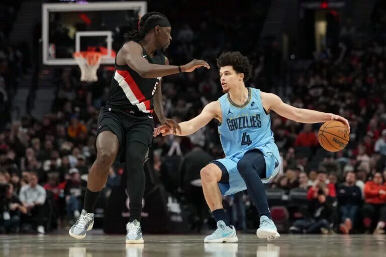 Feb 7, 2026; Portland, Oregon, USA; Memphis Grizzlies guard Walter Clayton Jr. (4) handles the ball against Portland Trail Blazers guard Jrue Holiday (5) during the second half at Moda Center. Mandatory Credit: Soobum Im-Imagn Images