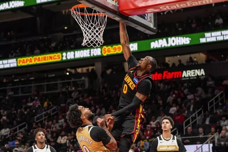 Feb 24, 2026; Atlanta, Georgia, USA; Atlanta Hawks forward Jonathan Kuminga (0) scores over Washington Wizards forward Justin Champagnie (9) during the second half at State Farm Arena. Mandatory Credit: Dale Zanine-Imagn Images