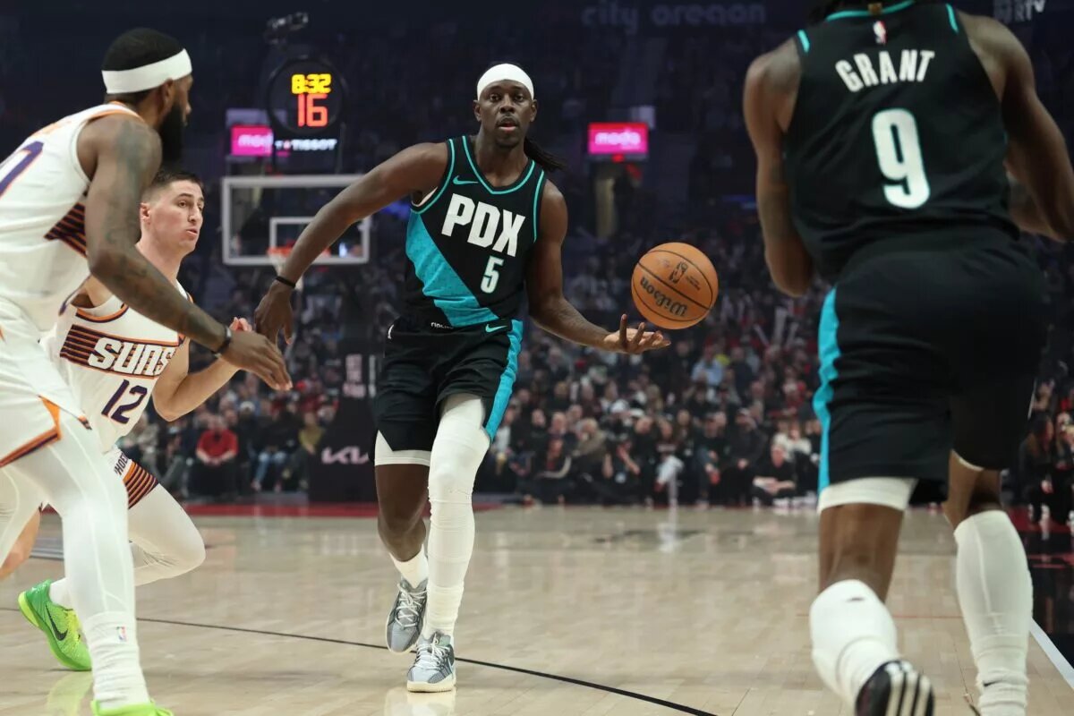 Feb 3, 2026; Portland, Oregon, USA; Portland Trail Blazers guard Jrue Holiday (5) passes the ball to teammate forward Jerami Grant (9) against Phoenix Suns guard Collin Gillespie (12) during the first half at Moda Center. Mandatory Credit: Jaime Valdez-Imagn Images