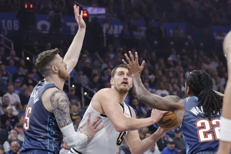 Feb 27, 2026; Oklahoma City, Oklahoma, USA; Denver Nuggets center Nikola Jokić (15) is defended by Oklahoma City Thunder center/forward Isaiah Hartenstein (55) and guard Cason Wallace (22) on a drive to the basket during the first quarter at Paycom Center. Mandatory Credit: Alonzo Adams-Imagn Images
