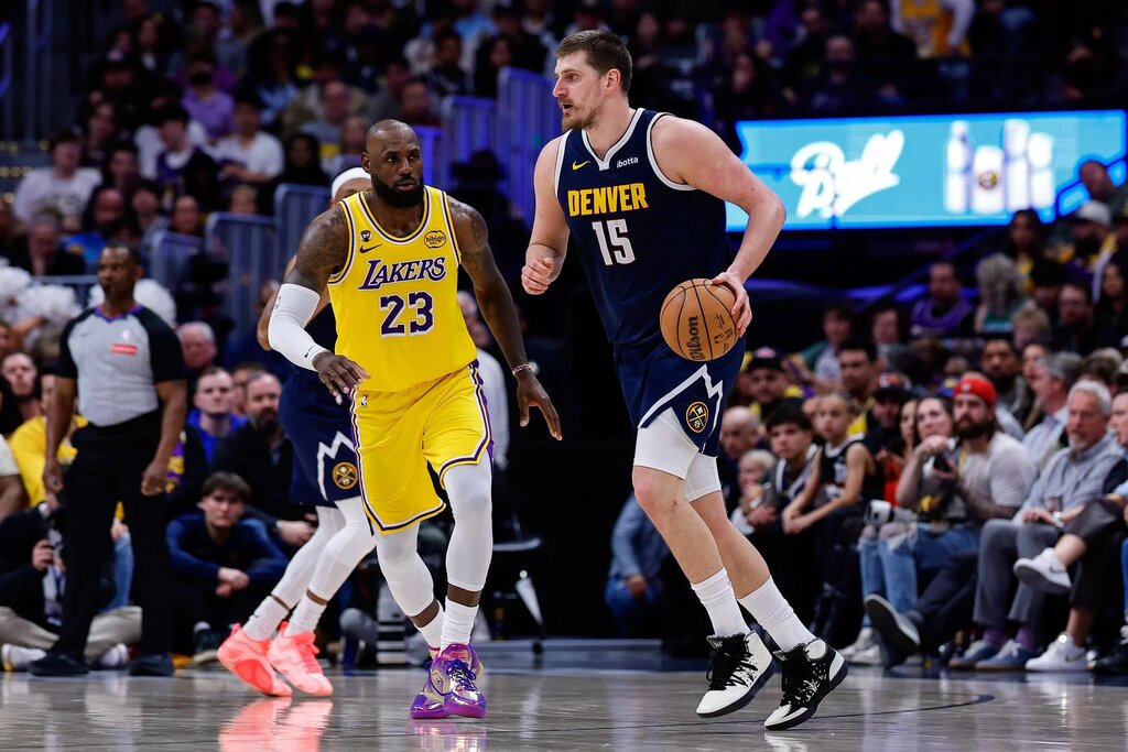Denver Nuggets center Nikola Jokic (15) controls the ball as Los Angeles Lakers forward LeBron James (23) guards in the fourth quarter at Ball Arena.