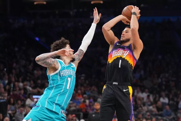 Mar 8, 2026; Phoenix, Arizona, USA; Phoenix Suns guard Devin Booker (1) shoots over Charlotte Hornets guard LaMelo Ball (1) during the second half at Mortgage Matchup Center. Mandatory Credit: Joe Camporeale-Imagn Images