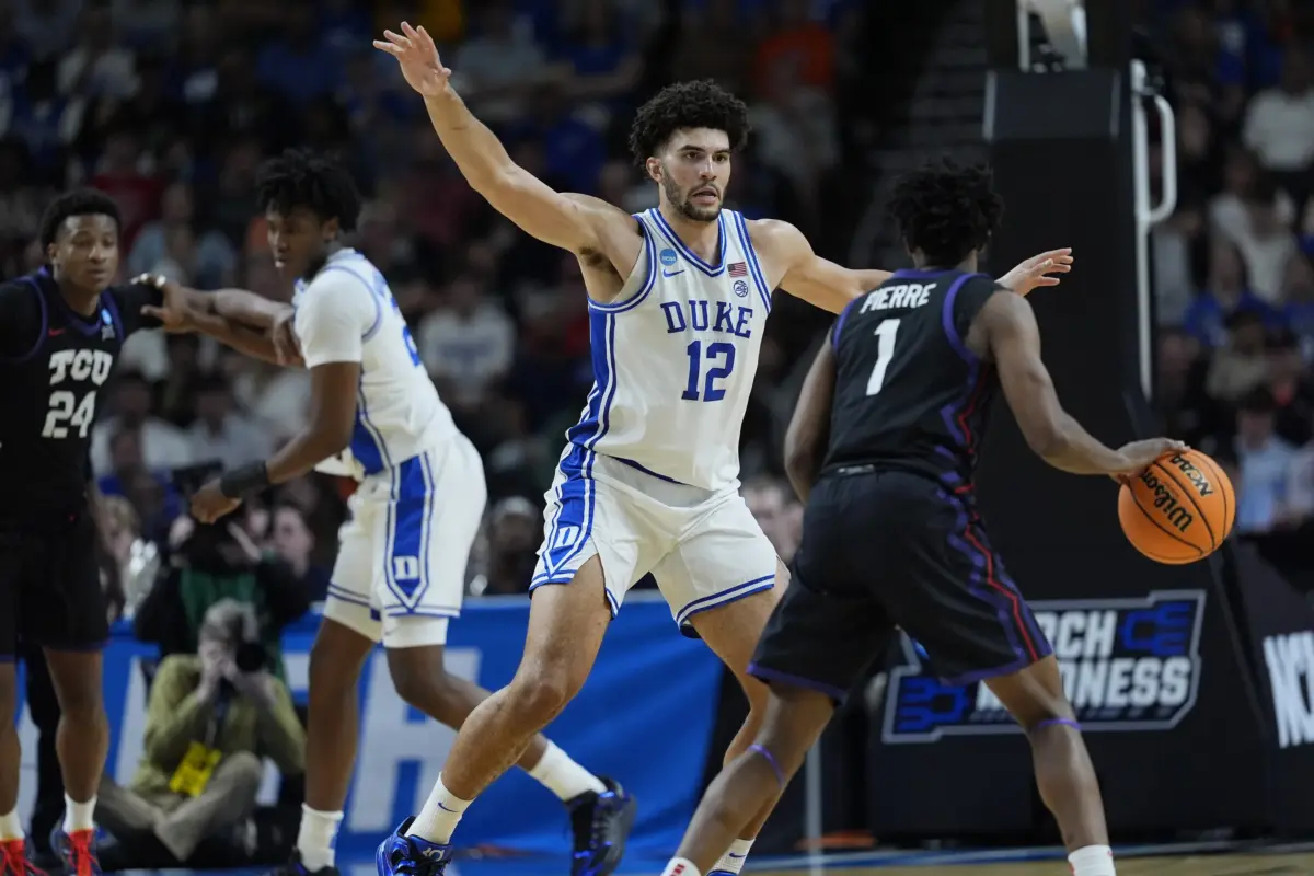 Duke Blue Devils forward Cameron Boozer (12) defends against Texas Christian University Horned Frogs guard Jayden Pierre (1) during a second round game of the men's 2026 NCAA Tournament at Bon Secours Wellness Arena.