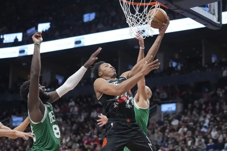 Dec 7, 2025; Toronto, Ontario, CAN; Toronto Raptors guard Scottie Barnes (4) goes up to make a basket against Boston Celtics center Neemias Queta (88) and guard Derrick White (9) during the second half at Scotiabank Arena. Mandatory Credit: John E. Sokolowski-Imagn Images