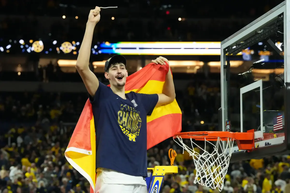 Michigan Wolverines center Aday Mara (15) celebrates after cutting down a piece of the net after defeating the Connecticut Huskies in the national championship of the Final Four of the men's 2026 NCAA Tournament at Lucas Oil Stadium.