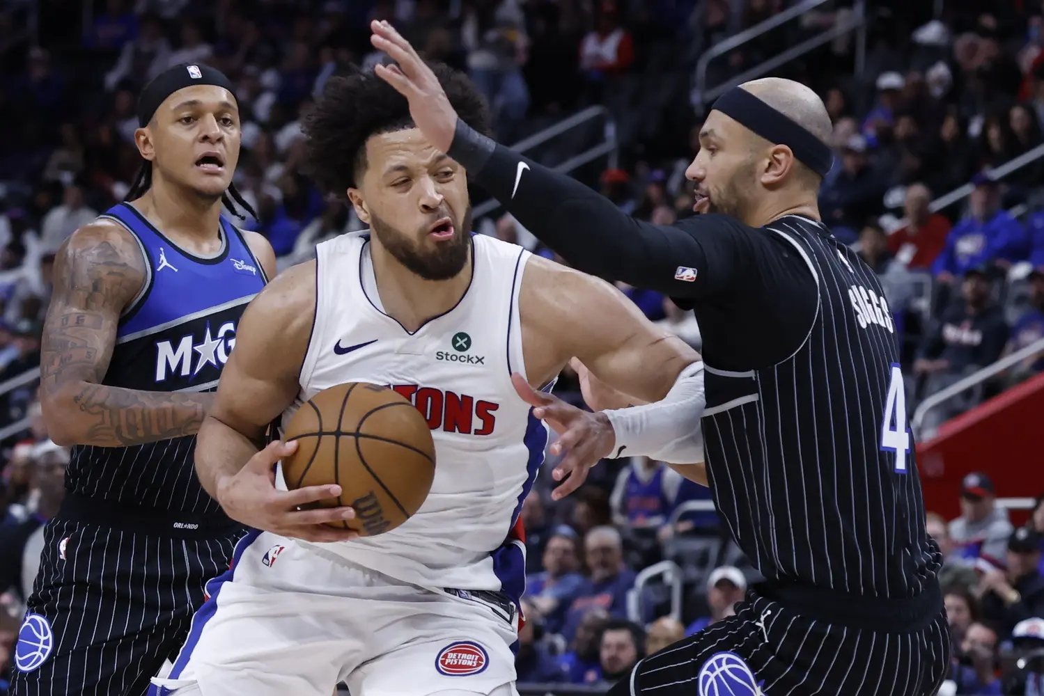 Detroit Pistons guard Cade Cunningham drives to the rim against Orlando Magic guard Jalen Suggs while Paolo Banchero comes in from behind