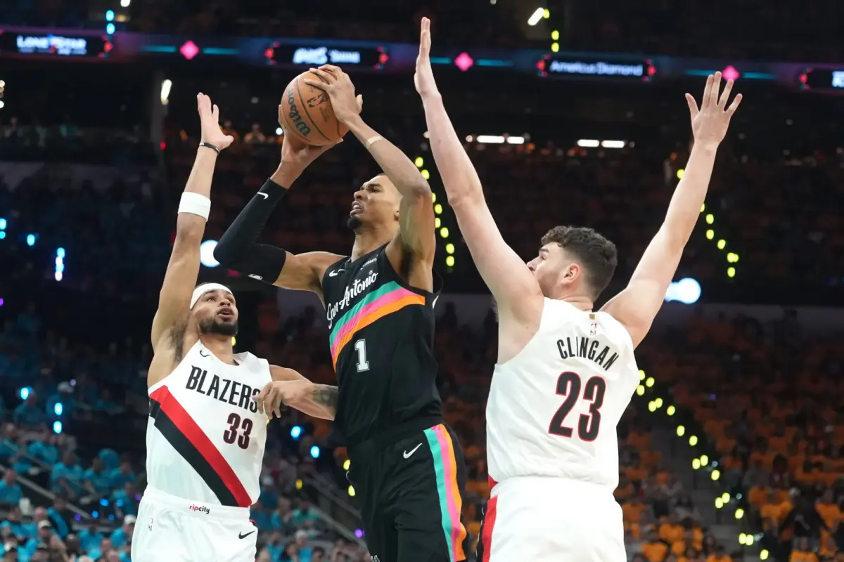 San Antonio Spurs forward Victor Wembanyama (1) drives to the basket between Portland Trail Blazers forward Toumani Camara (33) and center Donovan Clingan (23) during the first half of game one of the first round of the 2026 NBA Playoffs at Frost Bank Center.