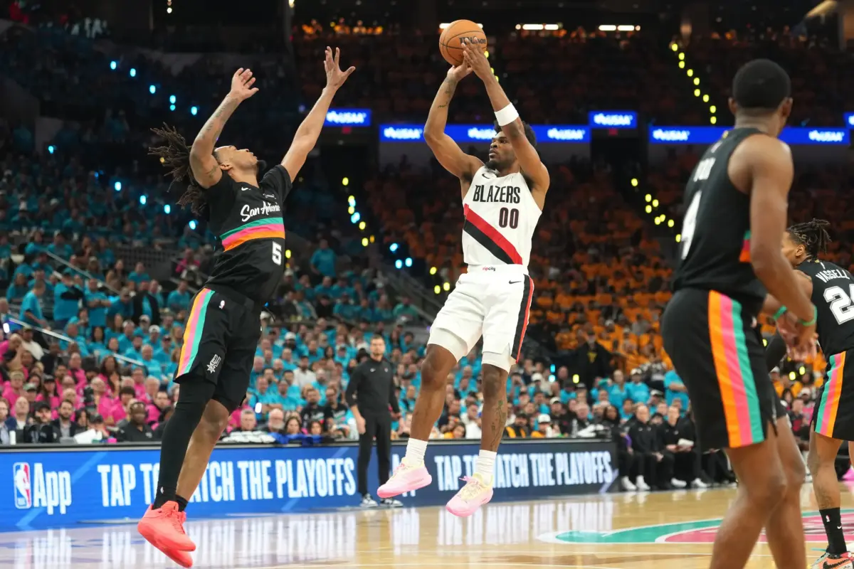 Portland Trail Blazers guard Scoot Henderson (0) shoots over San Antonio Spurs guard Devin Vassell (24) during the second half of game one of the first round of the 2026 NBA Playoffs at Frost Bank Center.
