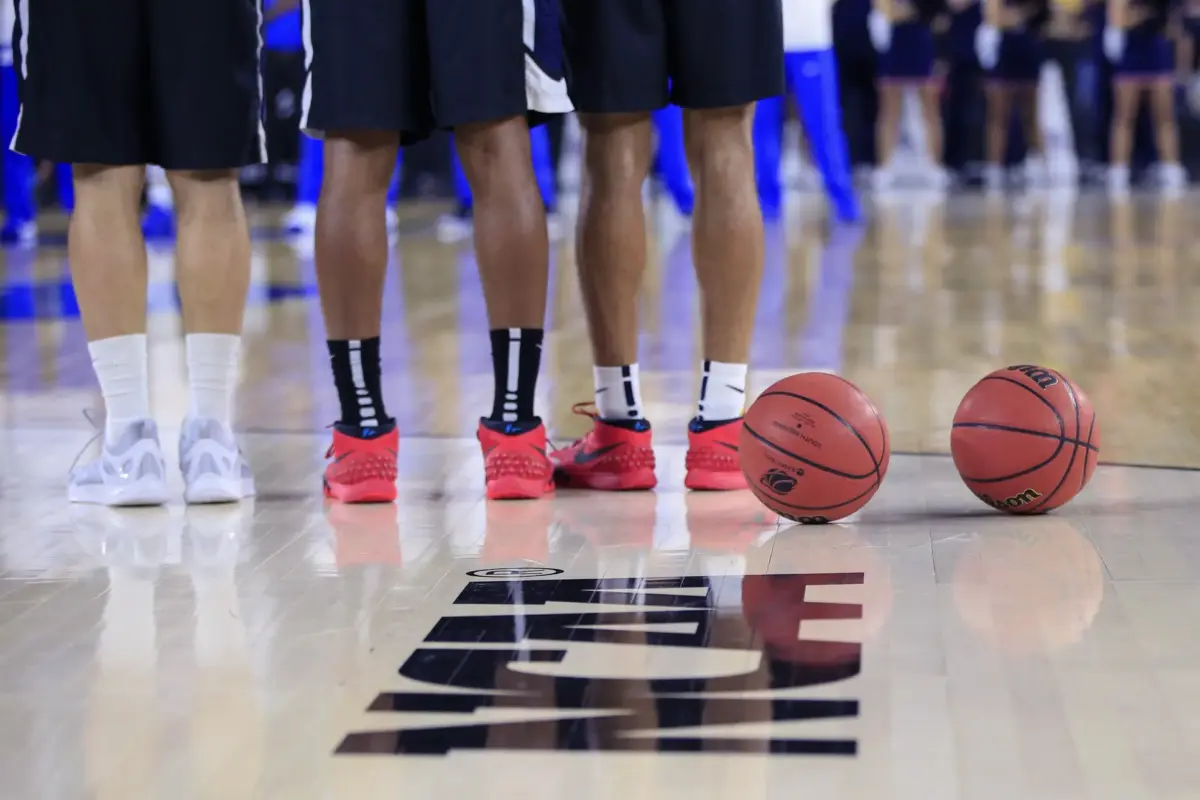 A bottom-half view of Duke Blue Devils players standing alongside each other in front of the NCAA logo