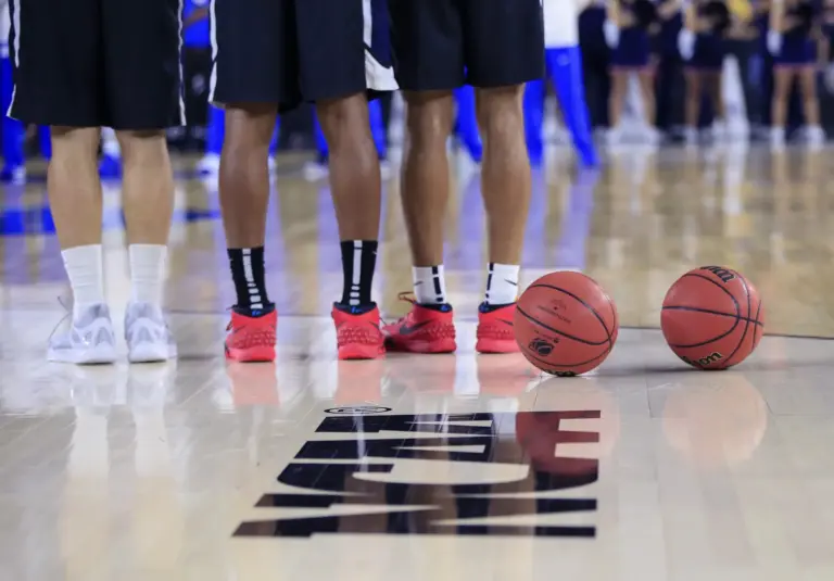 A bottom-half view of Duke Blue Devils players standing alongside each other in front of the NCAA logo