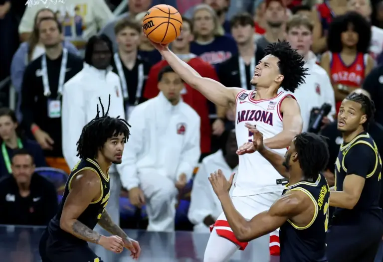 Arizona Wildcats guard Brayden Burries (5) goes to the basket against Michigan Wolverines forward Morez Johnson Jr. (21) in the second half during a semifinal of the Final Four of the men's 2026 NCAA Tournament at Lucas Oil Stadium.