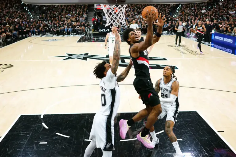 Apr 21, 2026; San Antonio, Texas, USA; Portland Trail Blazers guard Scoot Henderson (0) drives between forward Julian Champagnie (30) and guard Devin Vassell (24) during the first half of game two of the first round of the 2026 NBA Playoffs against the San Antonio Spurs at Frost Bank Center. Mandatory Credit: Scott Wachter-Imagn Images