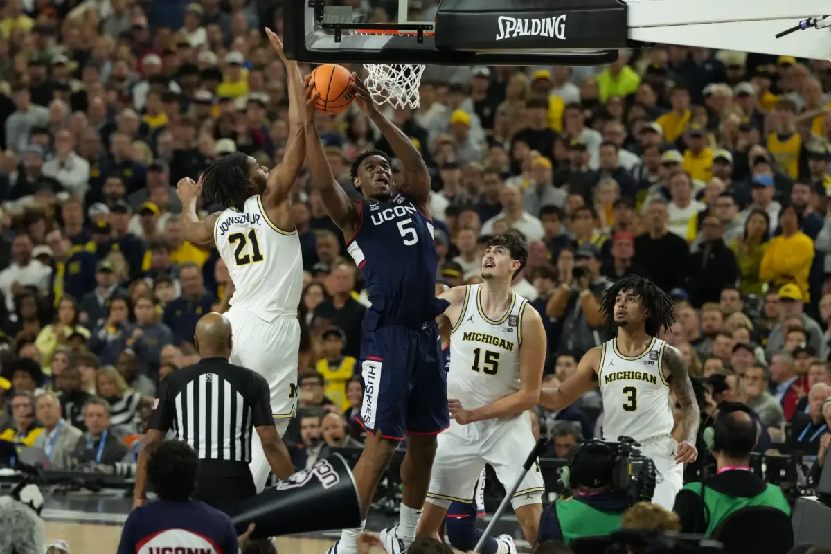 Michigan Wolverines forward Morez Johnson Jr. (21) defends against Connecticut Huskies forward Tarris Reed Jr. (5) in the second half during the national championship of the Final Four of the men's 2026 NCAA Tournament at Lucas Oil Stadium.