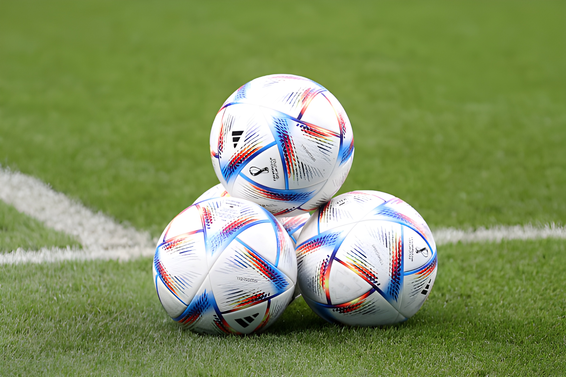 Three 2022 World Cup footballs on pitch in Qatar