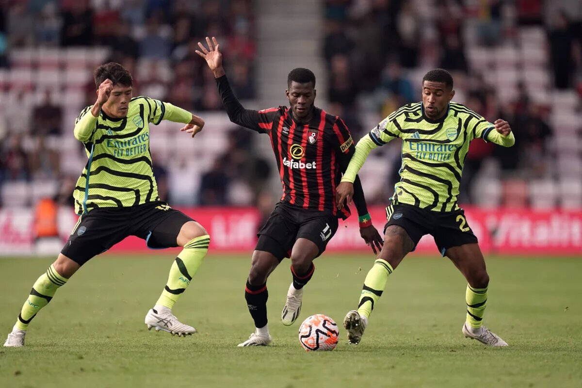 Arsenal's Takehiro Tomiyasu and Reiss Nelson battle Bournemouth's Dango Ouattara for the ball.