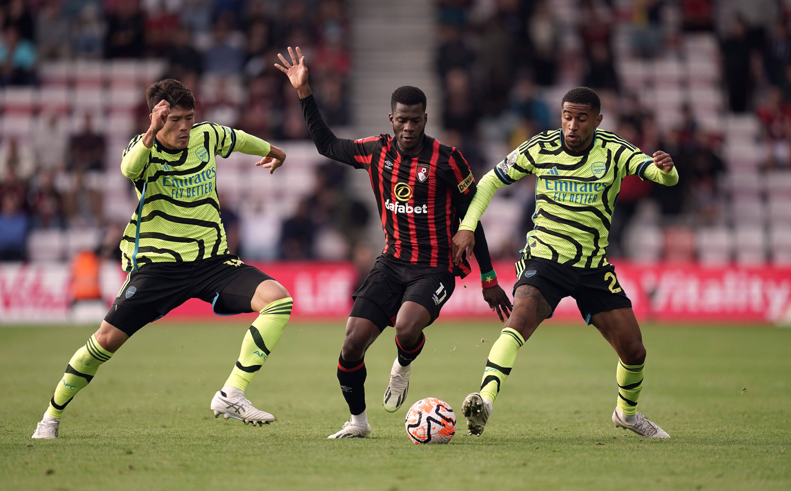 Arsenal's Takehiro Tomiyasu and Reiss Nelson battle Bournemouth's Dango Ouattara for the ball.